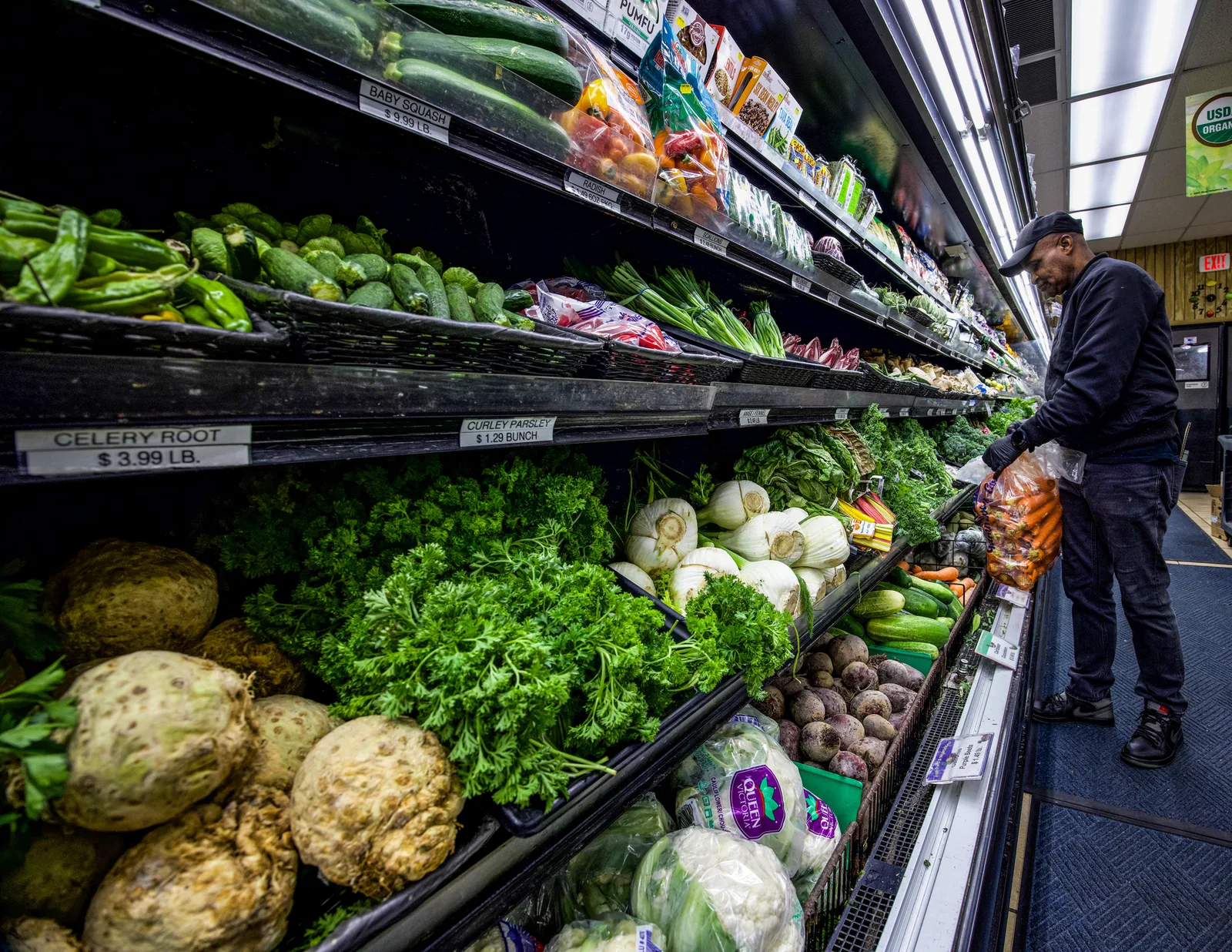 Team member arranging vegetables in the produce section at The Fruit Bowl.